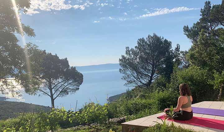 how to become a digital nomad - woman doing yoga in front of sea