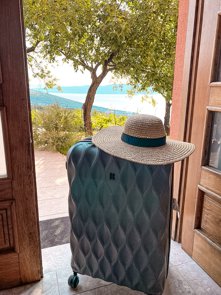 best time to visit croatia - suitcase with summer hat in front of sea