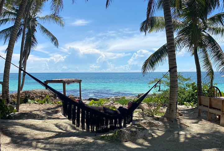 how to become a digital nomad - girl lying in hammock under palm trees by the beach