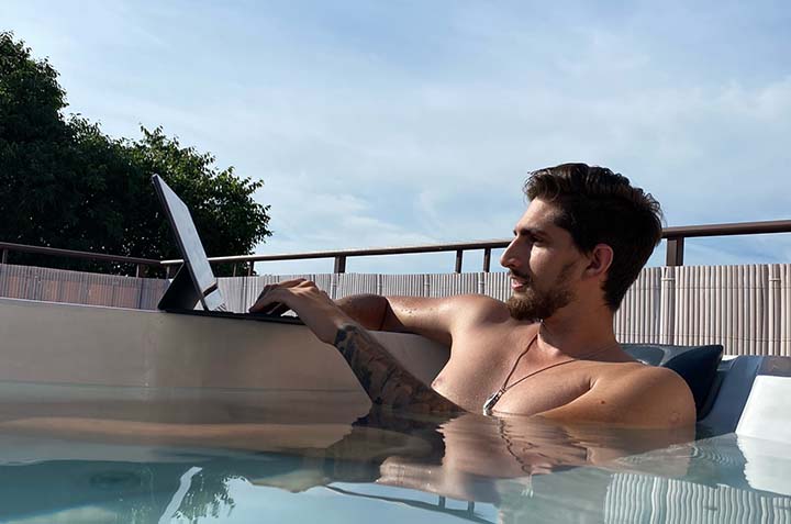 how to become a digital nomad - man in hot tub working on tablet