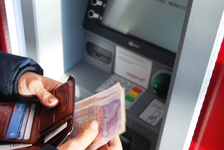 best banks for digital nomads - man at ATM holding cash
