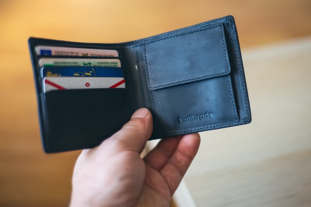 man holding an open wallet full of credit cards